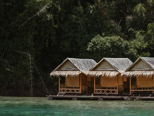 Three wooden cabins beside clear tropical water